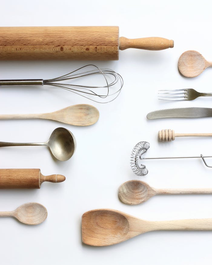 The Art of Drawing Readers In: Your attractive post title goes here 3 Wooden and metal kitchen utensils arranged on a white backdrop in a flat lay style.